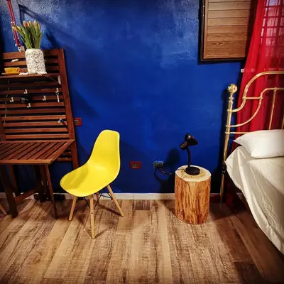 a bedroom with a yellow chair and a blue wall at CasuzzaMia in Palermo