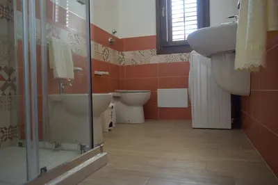 a bathroom with two toilets and a sink and a shower at Acqua Chiara Appartamenti in San Vito lo Capo