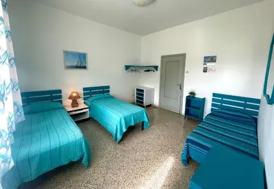 two beds in a room with blue sheets at Sea Front in Carini