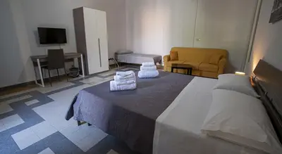 a bedroom with a bed and a couch and a television at GiaChi friendly rooms alla Stazione in Palermo