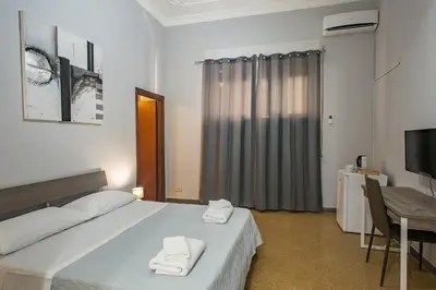 a bedroom with a bed and a table and a television at GiaChi friendly rooms alla Stazione in Palermo