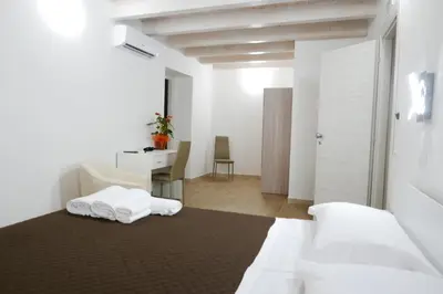 a bedroom with a bed with white sheets and a desk at Opera Boutique Rooms in Monreale