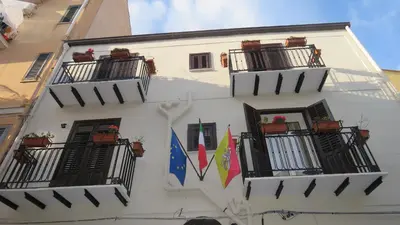 a white building with balconies and flags on it at Opera Boutique Rooms in Monreale