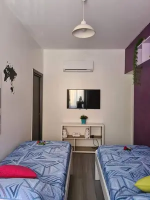 a bedroom with two beds and a tv on the wall at Casa Le Rose in Palermo