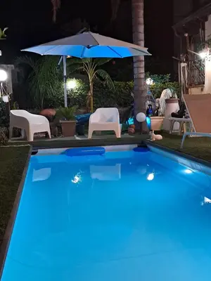 a swimming pool at night with an umbrella and chairs at Casa Le Rose in Palermo