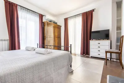 a bedroom with a bed and a tv and curtains at Teatro Massimo City Center Apartments in Palermo