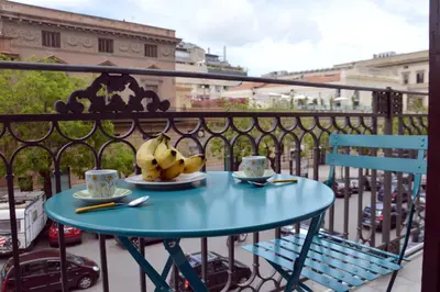 a blue table on a balcony with two cups and bananas at Teatro Massimo City Center Apartments in Palermo