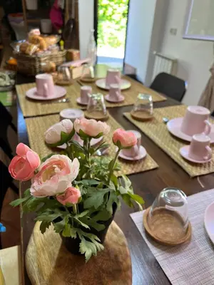 a wooden table with pink flowers in a vase on it at Lisetta's house in Monreale