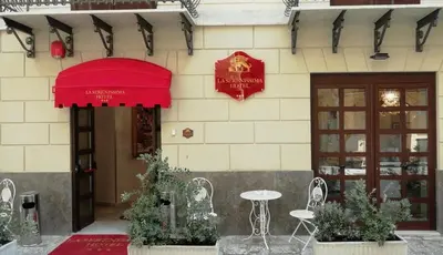 a building with a red umbrella and a table and chairs at La Serenissima Hotel in Palermo
