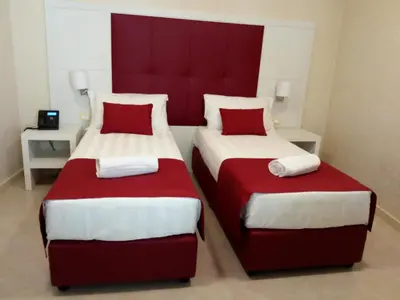 two beds in a room with red and white at La Serenissima Hotel in Palermo