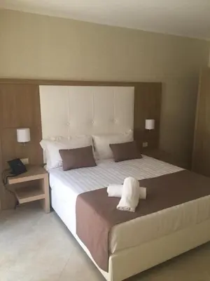 a bedroom with a large white bed with two lamps at La Serenissima Hotel in Palermo