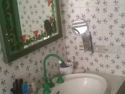 a bathroom sink with a green faucet and a mirror at Gibellina Home in Nuova Gibellina