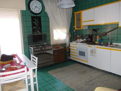 a kitchen with green tiles and a clock on the wall at Gibellina Home in Nuova Gibellina