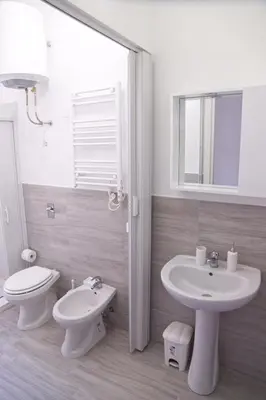a white bathroom with a toilet and a sink at Clambè in Palermo