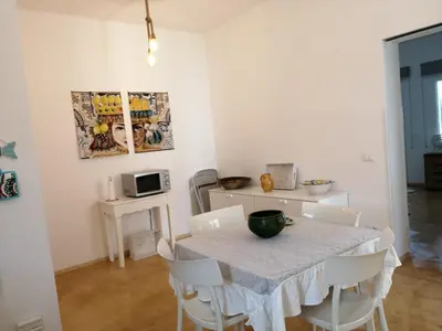 a dining room with a table and white chairs at Villa Acquamarina sul mare in San Vito lo Capo