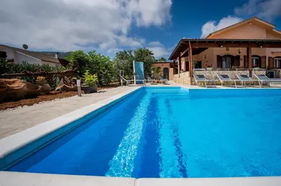 a blue swimming pool with chairs and a house at Villa Mirto in Castellammare del Golfo