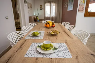 a wooden table with a bowl of fruit and two cups at Villa Mirto in Castellammare del Golfo