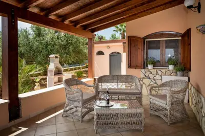a patio with wicker chairs and a table at Villa Mirto in Castellammare del Golfo