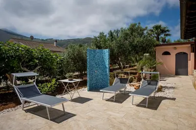 a group of chairs and a blue sculpture on a patio at Villa Mirto in Castellammare del Golfo