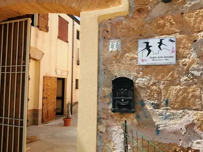 a sign on the side of a stone wall with a mailbox at Baglio delle Rondini in Bagheria