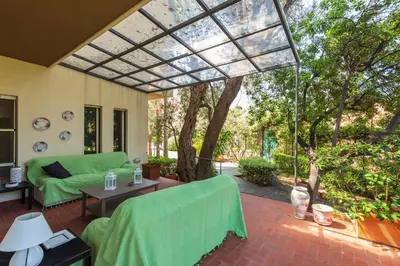a screened in porch with a green couch and a swing at Domus Sicily - Villa Conca d'Oro with Pool in Palermo