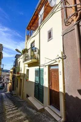 a building with green doors on a street at B&B Chiaro di Luna in Corleone
