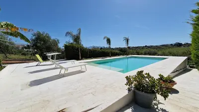 a swimming pool with a chair and a table at Villa Stella Cinese in Alcamo