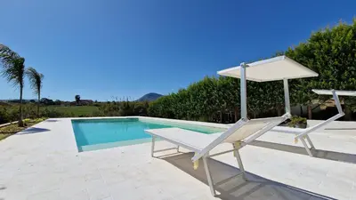 a chair and an umbrella next to a swimming pool at Villa Stella Cinese in Alcamo