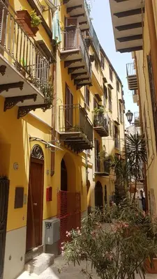 a yellow building with balconies and flowers on a street at Casuzza Ballarò in Palermo