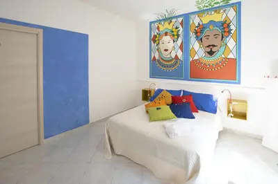 a bedroom with a bed with paintings on the wall at Casuzza Ballarò in Palermo