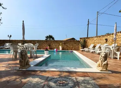 a swimming pool with white chairs and a table and a pool at Case Vacanza Zeus in Trappeto