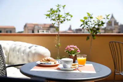 a table with a plate of food and a cup of orange juice at Residenza Normanna in Palermo