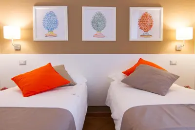 two beds with orange and grey pillows in a room at Residenza Normanna in Palermo