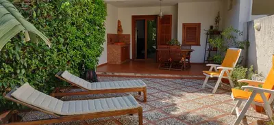 a patio with chairs and a table and a bush at Villetta a due passi dal mare in Palermo