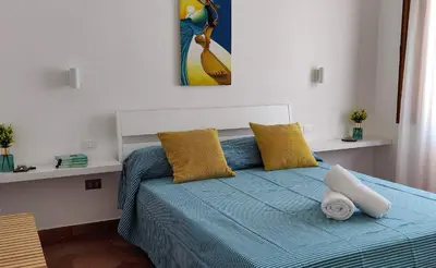 a bedroom with a blue bed with yellow pillows at Villetta a due passi dal mare in Palermo
