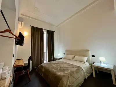 a bedroom with a bed and a desk and a window at Pupi 93 in Palermo