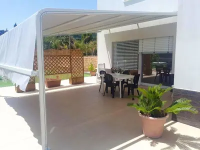 a patio with a table and chairs under awning at Spacious villa with sea and mountain views in Alcamo in Alcamo