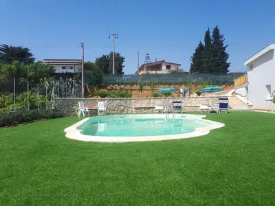 a small pool in a yard with chairs and umbrellas at Spacious villa with sea and mountain views in Alcamo in Alcamo