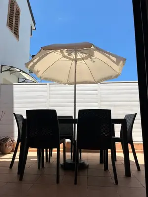 a table and chairs under an umbrella on a patio at Xenia House in Lascari