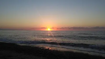 a sunset on the beach with the ocean at Xenia House in Lascari