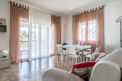 a dining room with a table and chairs and windows at La Maison De Provence - MONDELLO in Mondello