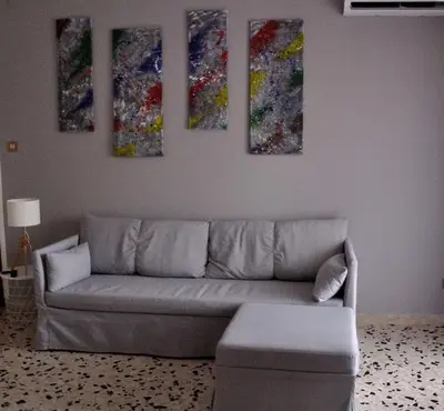 a living room with a couch and four paintings on the wall at Casa Rosetta in Palermo