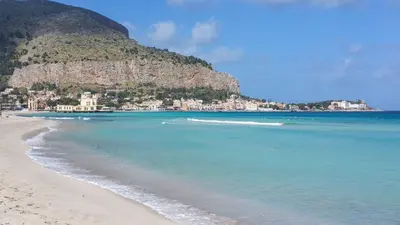 a view of a beach with a mountain in the background at Mondello Rose House in Palermo