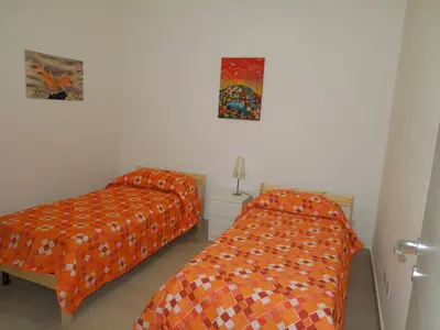 two beds in a room with orange sheets at Mondello Rose House in Palermo
