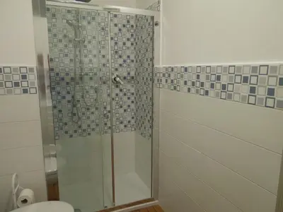 a bathroom with a glass shower with a toilet at Mondello Rose House in Palermo
