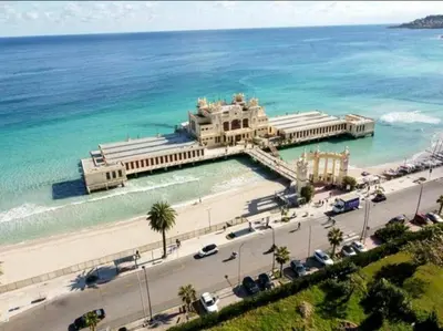 a building on a beach next to the ocean at Mondello Rose House in Palermo