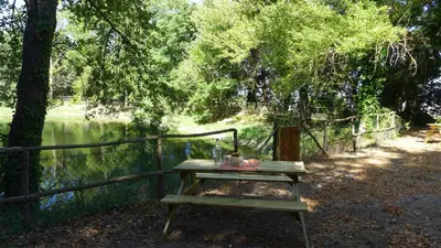 a picnic table next to a fence next to a lake at Chiosi Country Club in Corleone