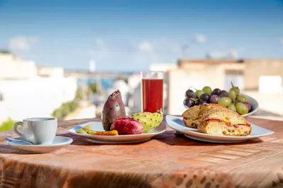 a table with plates of food and a cup of coffee at Agave Superior Rooms in San Vito lo Capo
