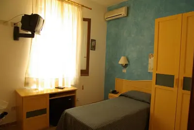 a bedroom with a bed and a desk and a window at Agave Superior Rooms in San Vito lo Capo