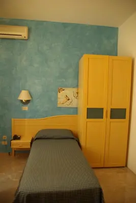 a bedroom with a bed and a yellow cabinet at Agave Superior Rooms in San Vito lo Capo